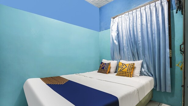 A neatly made bed with a blue and white bedspread, two patterned pillows, and a blue blanket. - OYO Homes 91009 Eco Tourism Desa Cibodas Areng 4 Syariah (Lembang)