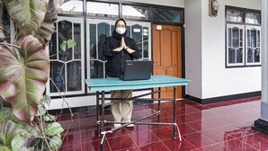 A person standing behind a table with a laptop, in a room with tiled flooring and large windows. - OYO Homes 91009 Eco Tourism Desa Cibodas Areng 4 Syariah (Lembang)