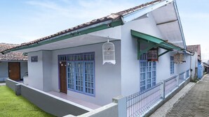 A house with a sloped roof, a balcony, and a birdcage hanging from the eaves. - OYO Homes 91009 Eco Tourism Desa Cibodas Areng 4 Syariah (Lembang)