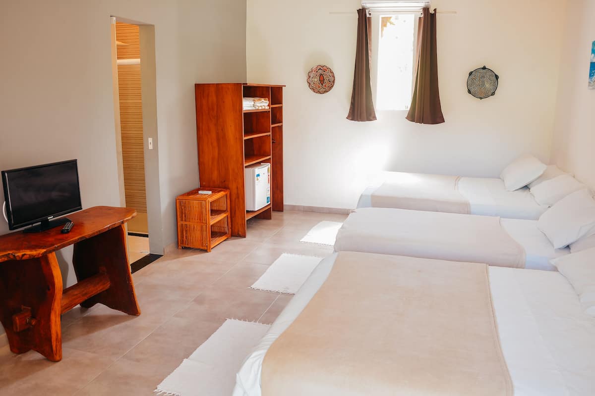 A bedroom with a bed, a wooden desk, a television, and a wardrobe.