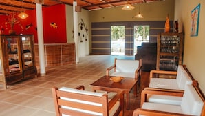 A spacious room with wooden furniture, a red accent wall, and a view to the outside. - Ajubá Pousada (Cairu)