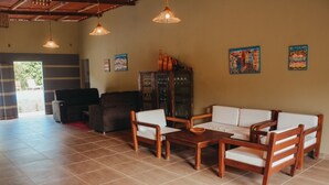 A spacious living area with a sofa set, wooden coffee table, and hanging pendant lights. - Ajubá Pousada (Cairu)