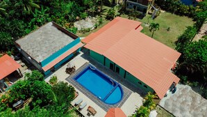 An aerial view of a property with a swimming pool, a covered patio, and surrounding greenery. - Ajubá Pousada (Cairu)