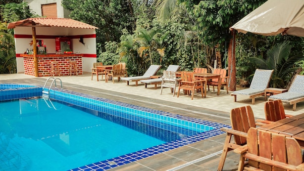 A pool area with a bar, lounge chairs, and a tiled deck. - Ajubá Pousada (Cairu)