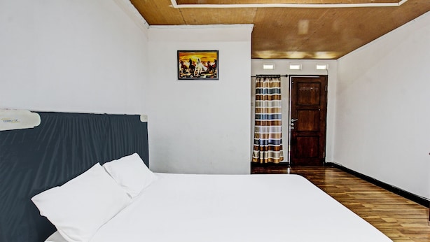 A bedroom with a bed, a wooden ceiling, a door, and a painting on the wall. - Hotel O Panorama Rinjani LodgeNearTaman Nasional Gunung Rinjani (Sembalun Lawang)