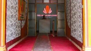 An entrance to a hotel with a red carpet, a reception desk, and a sign reading "The VIP Luxury Lounge".
