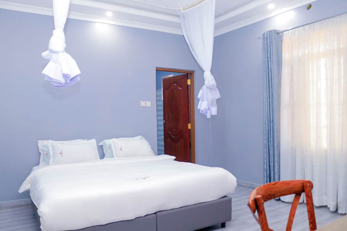 A bedroom with a bed, a wooden door, and a chair.
