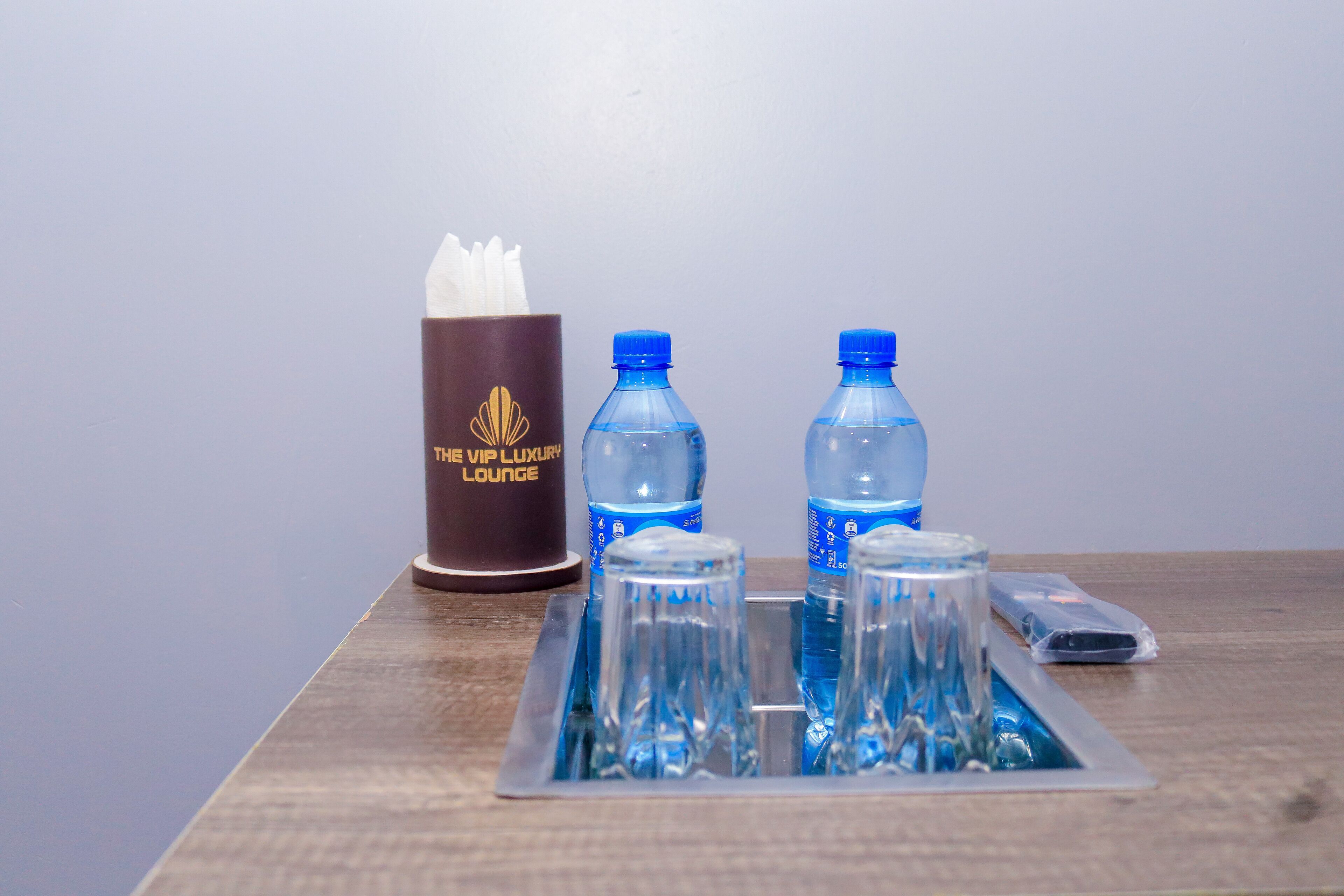 A tray with two water bottles and a tissue box on a wooden table.
