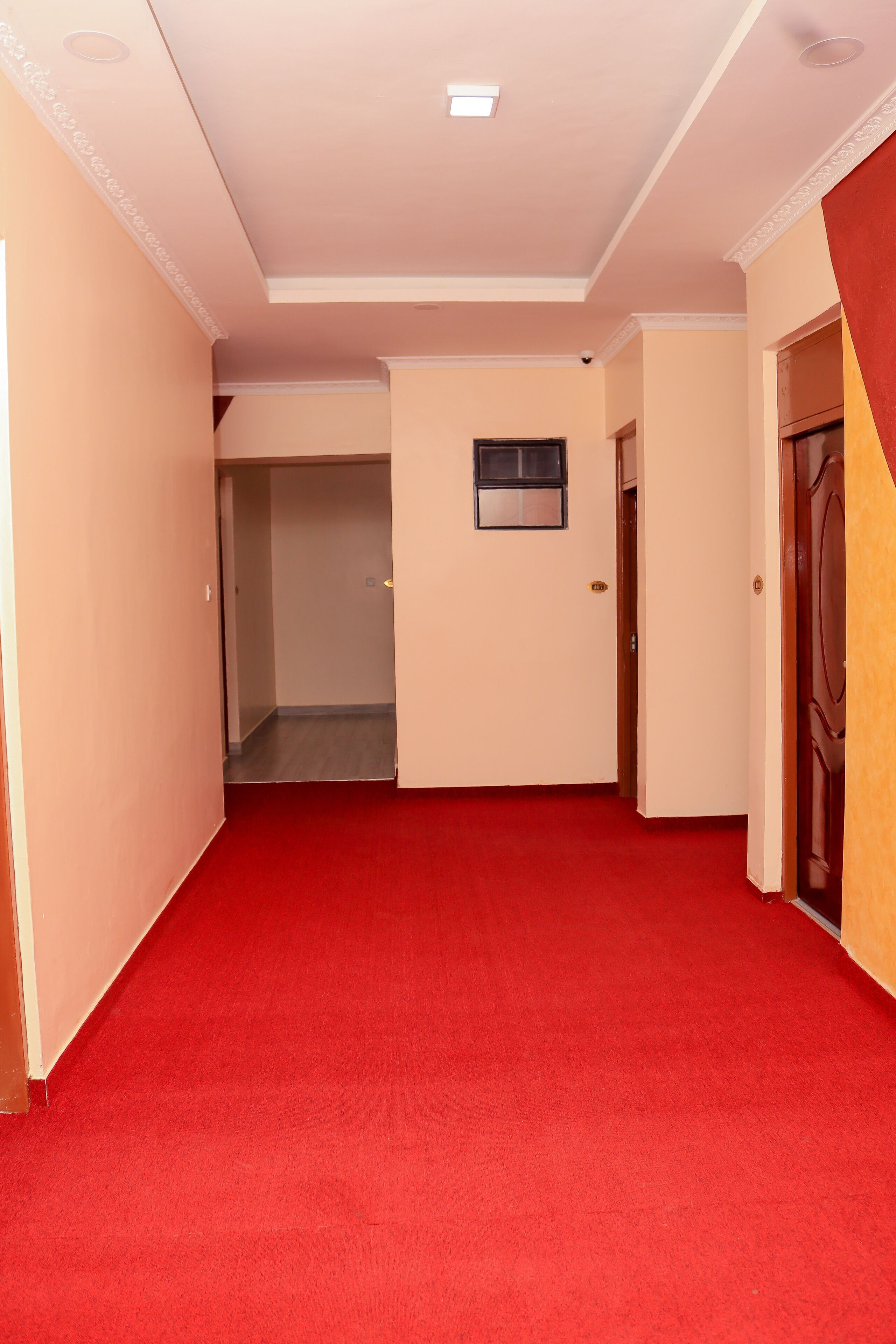 A hallway with red carpet, beige walls, and a door on the right.