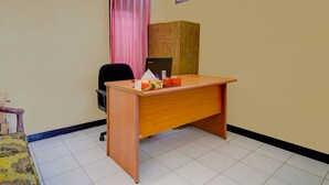 A room with a wooden desk, a black office chair, a pink curtain, a window, and a wooden cabinet. - OYO Life 91116 Pelangi Residence Syariah (Hegarmanah)