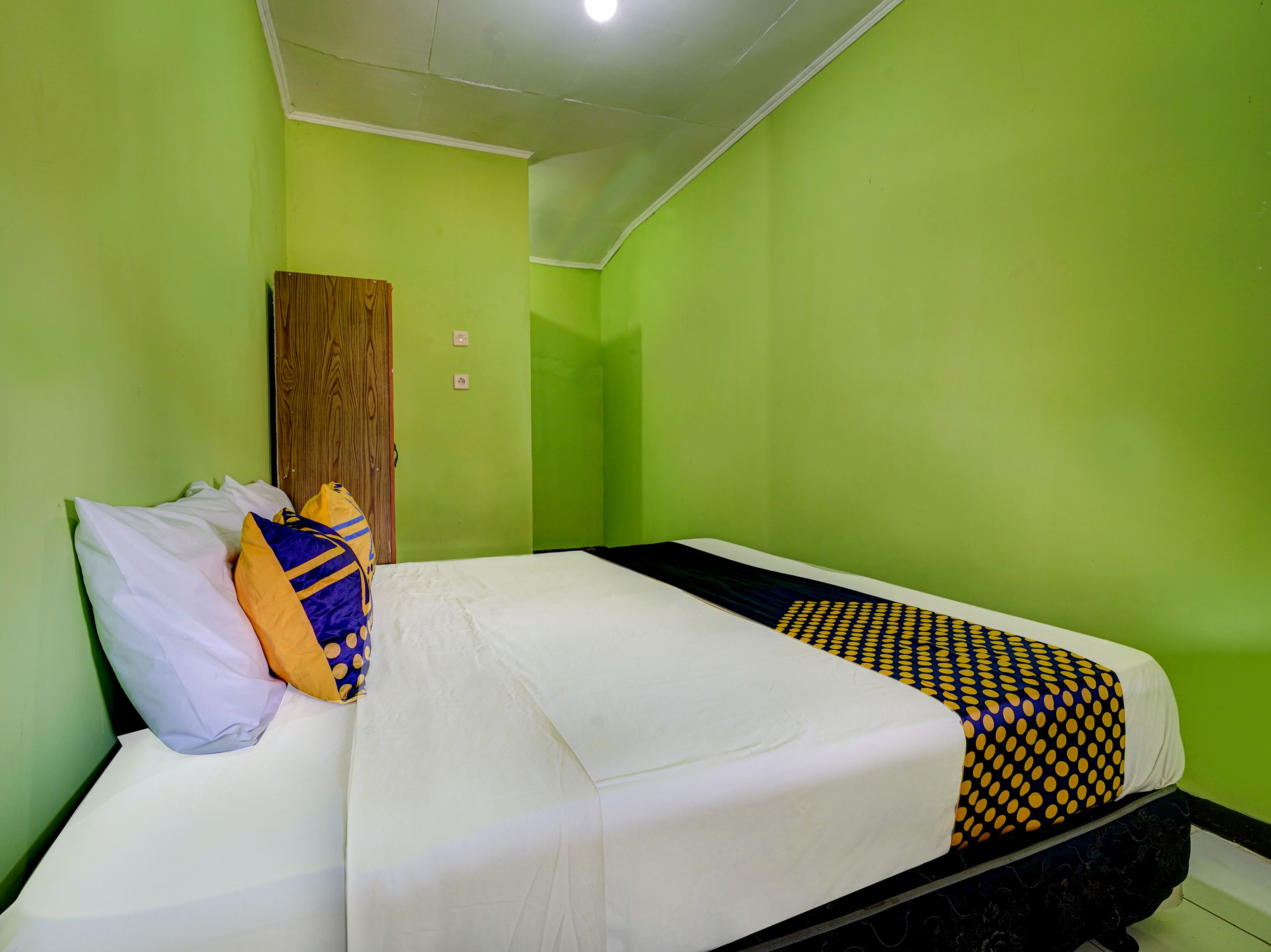 A room with a bed, pillows, and a wooden wardrobe.