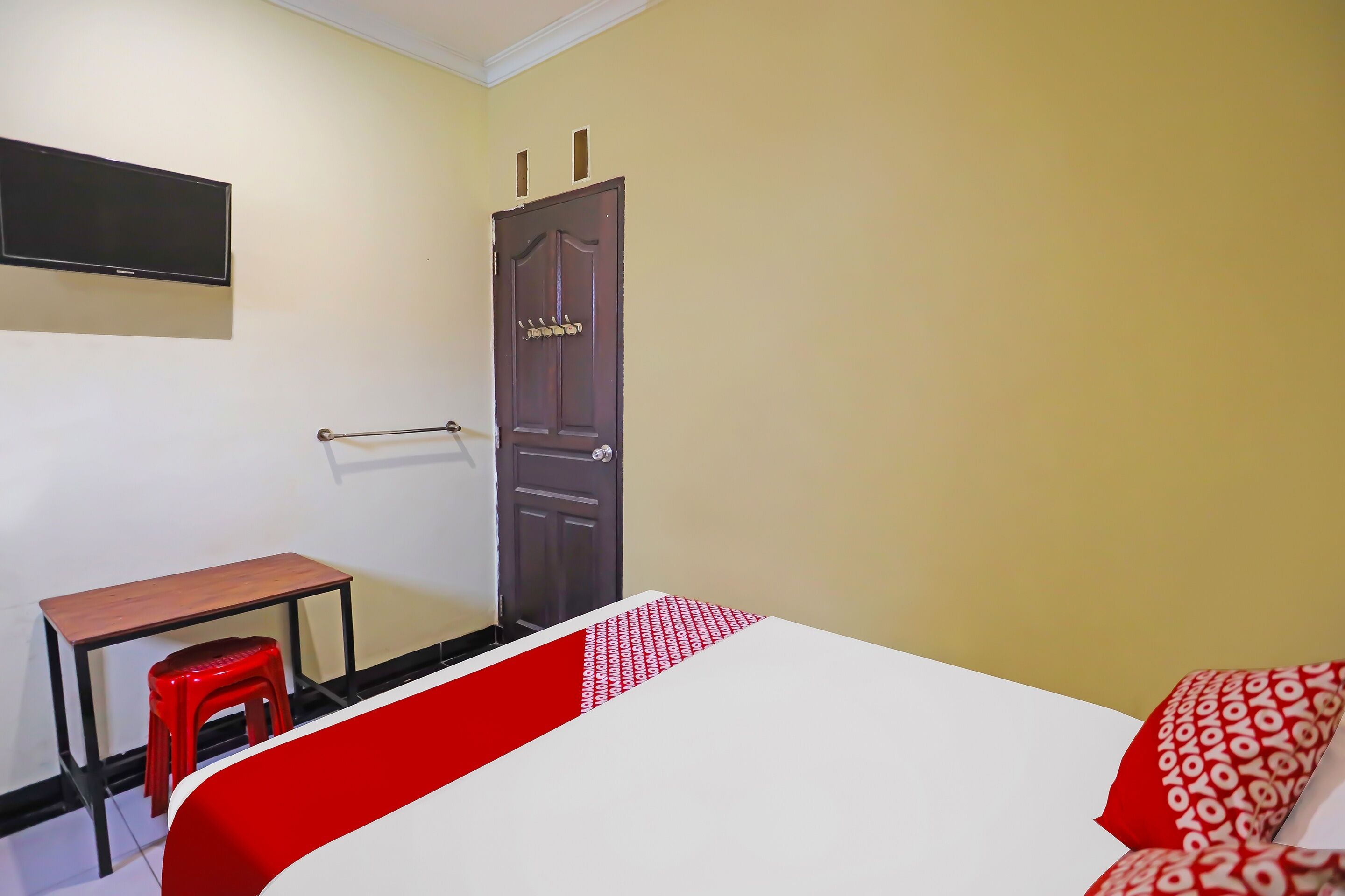 A room with a bed, a desk, a chair, and a door.
