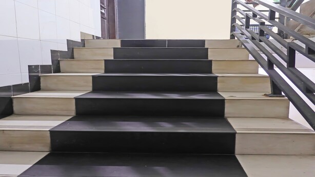 A set of black and beige stairs with a metal railing. - SPOT ON 92092 Wisma Nilam Sari Syariah (Batam)
