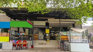 A street-side shop with a green awning, a motorcycle parked outside, and a staircase leading to the entrance. - SPOT ON 92092 Wisma Nilam Sari Syariah (Batam)