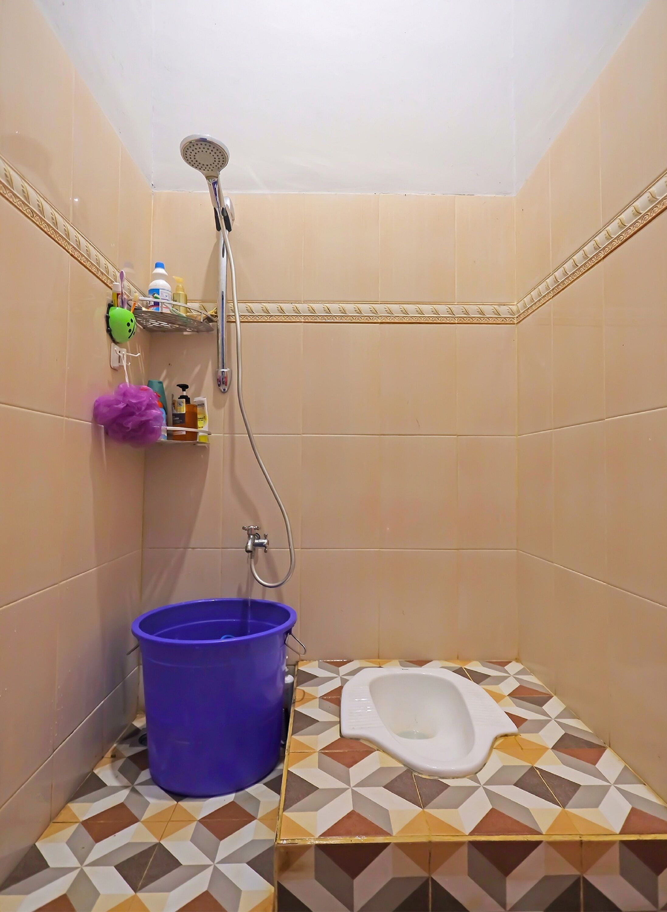 A bathroom with a shower, a toilet, and a blue bucket.