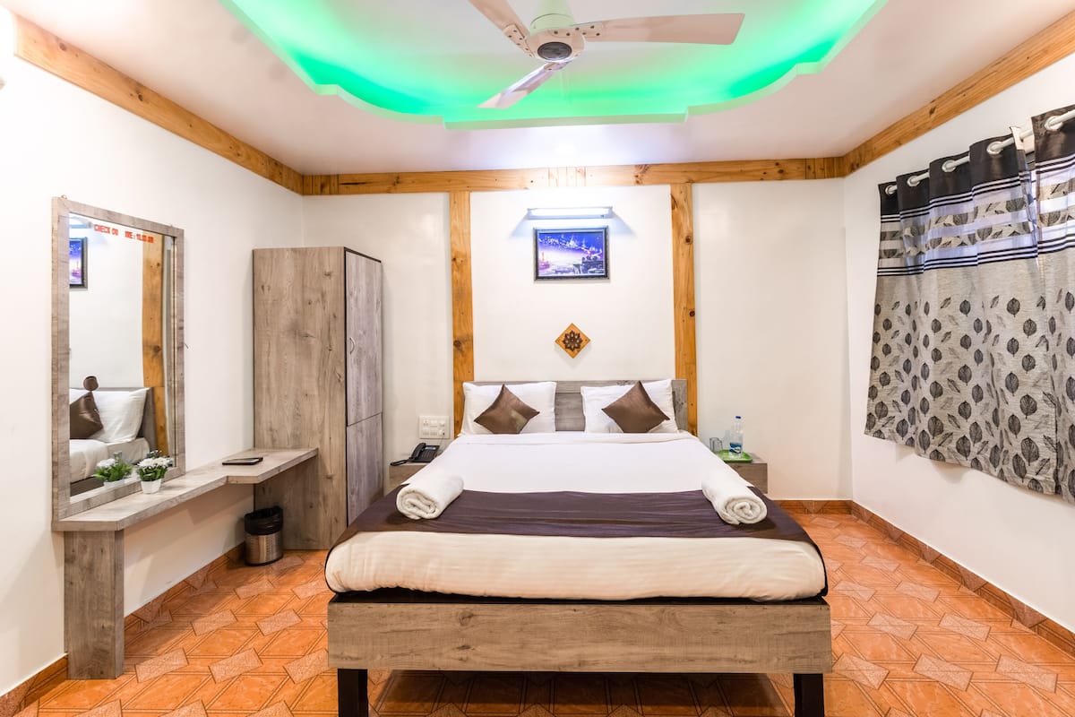 A hotel room with a wooden bed, a nightstand, a mirror, a wardrobe, and a ceiling fan.
