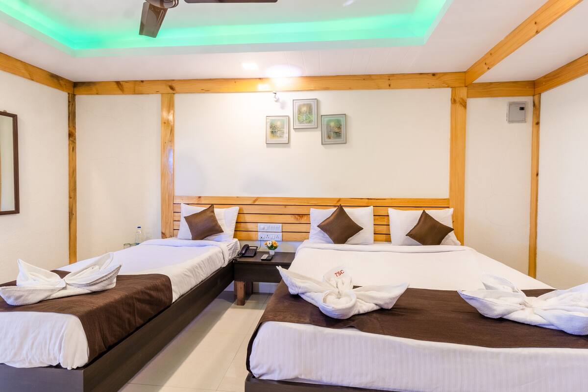 A hotel room with two beds, wooden headboards, a nightstand, and a ceiling fan.