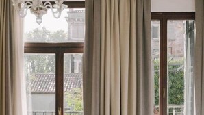 Un dormitorio con una cama grande, una araña y vistas a un balcón con cortinas.
