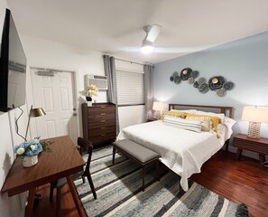 Cozy retreat with a neatly made bed, dresser, and desk area, complete with a ceiling fan and air conditioning unit.