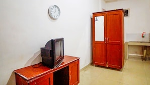A room with a wooden cabinet, a television, a clock on the wall, and a wardrobe.