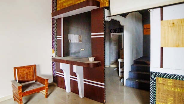 A bar area with a counter and a chair, a staircase, and a sign that reads "COFFEE".