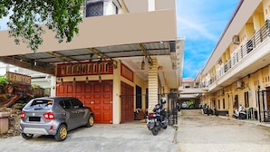 A residential area with a car and motorcycles parked in front of a building with a red door.