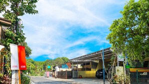 A street view with a building that has a covered entrance and a sign indicating a business. - Flagship 90723 Berlima Guest House Syariah (Malang)