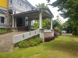 A two-story building with a covered entrance and a stone wall with numbers. - Hotel O Subur (Makassar)