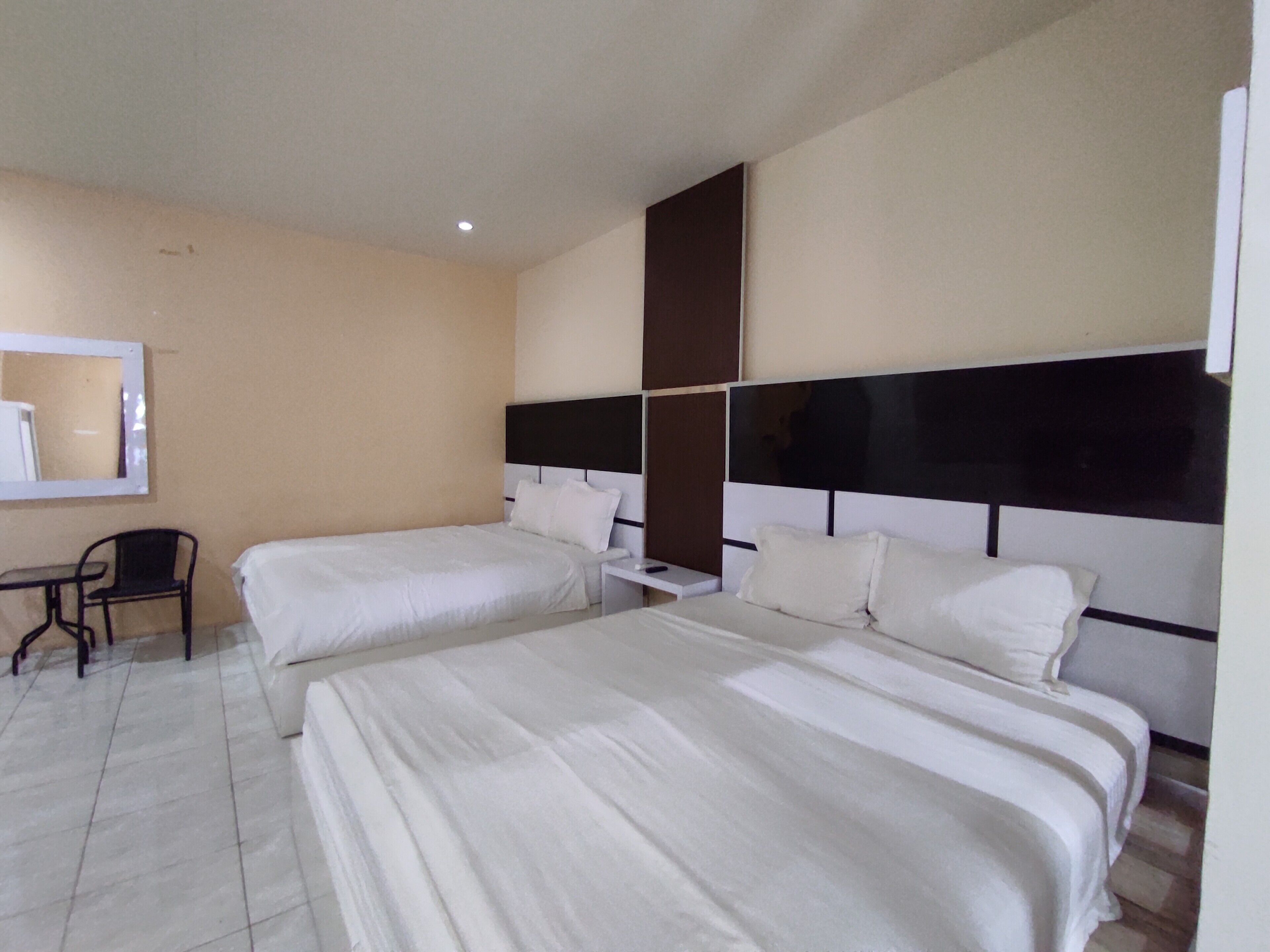 Une chambre d’hôtel avec deux lits, une petite table et une chaise.