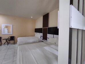 A hotel room with two beds, a small table, a chair, and a mirror on the wall. - Hotel O Subur (Makassar)