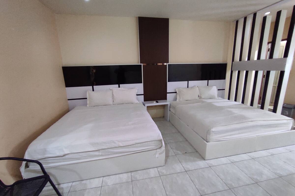 A hotel room with two beds, a desk, and a chair.