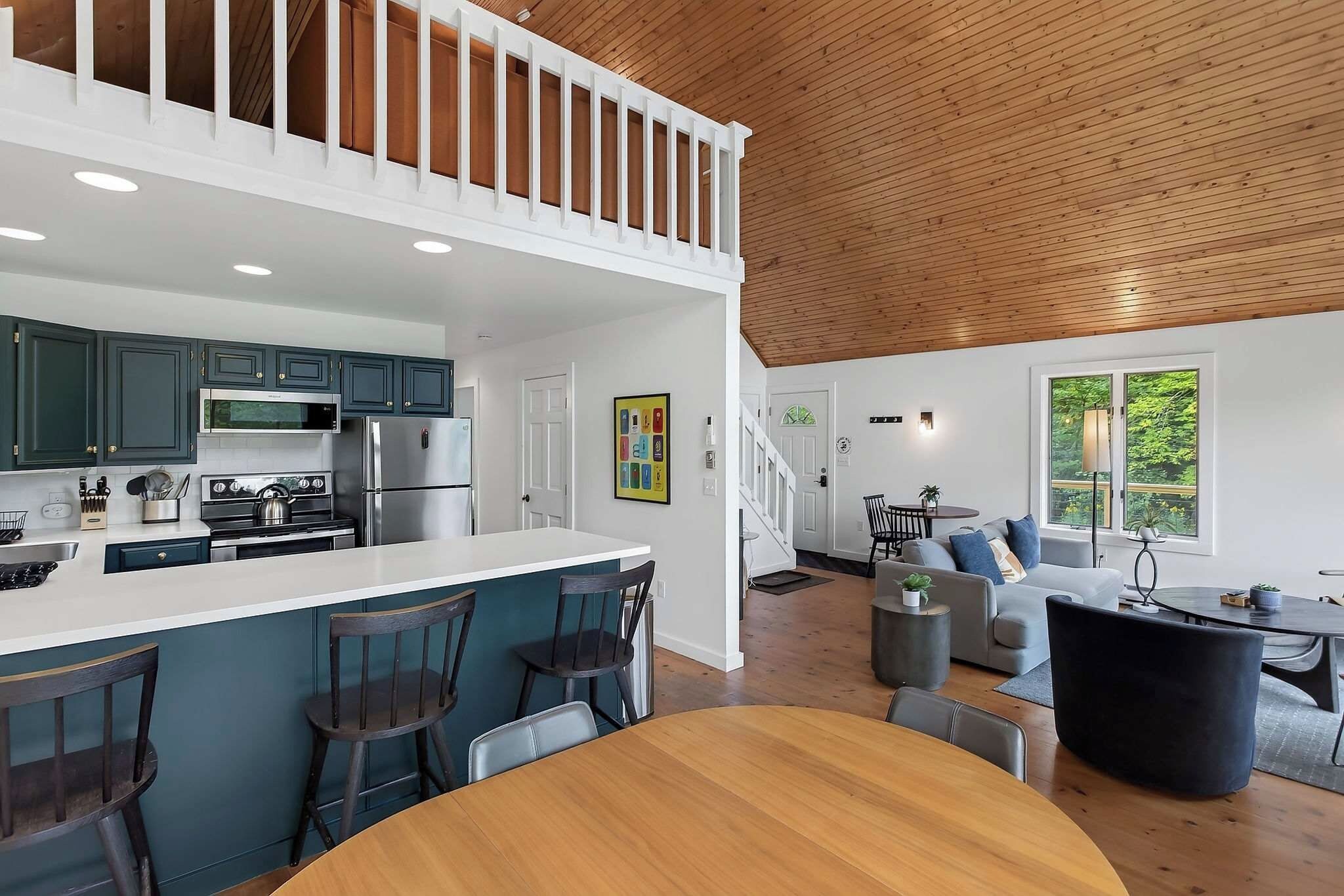 A modern kitchen with a central island, dining area with a round table, and a living space with a sofa and a coffee table.