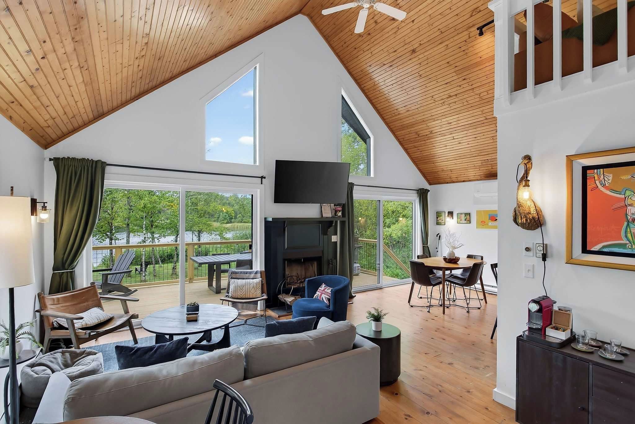 A spacious living area with a high ceiling, a fireplace, and a dining area with a table and chairs.