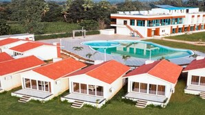 A resort with multiple bungalow-style accommodations, a central swimming pool, and a view of the surrounding landscape.