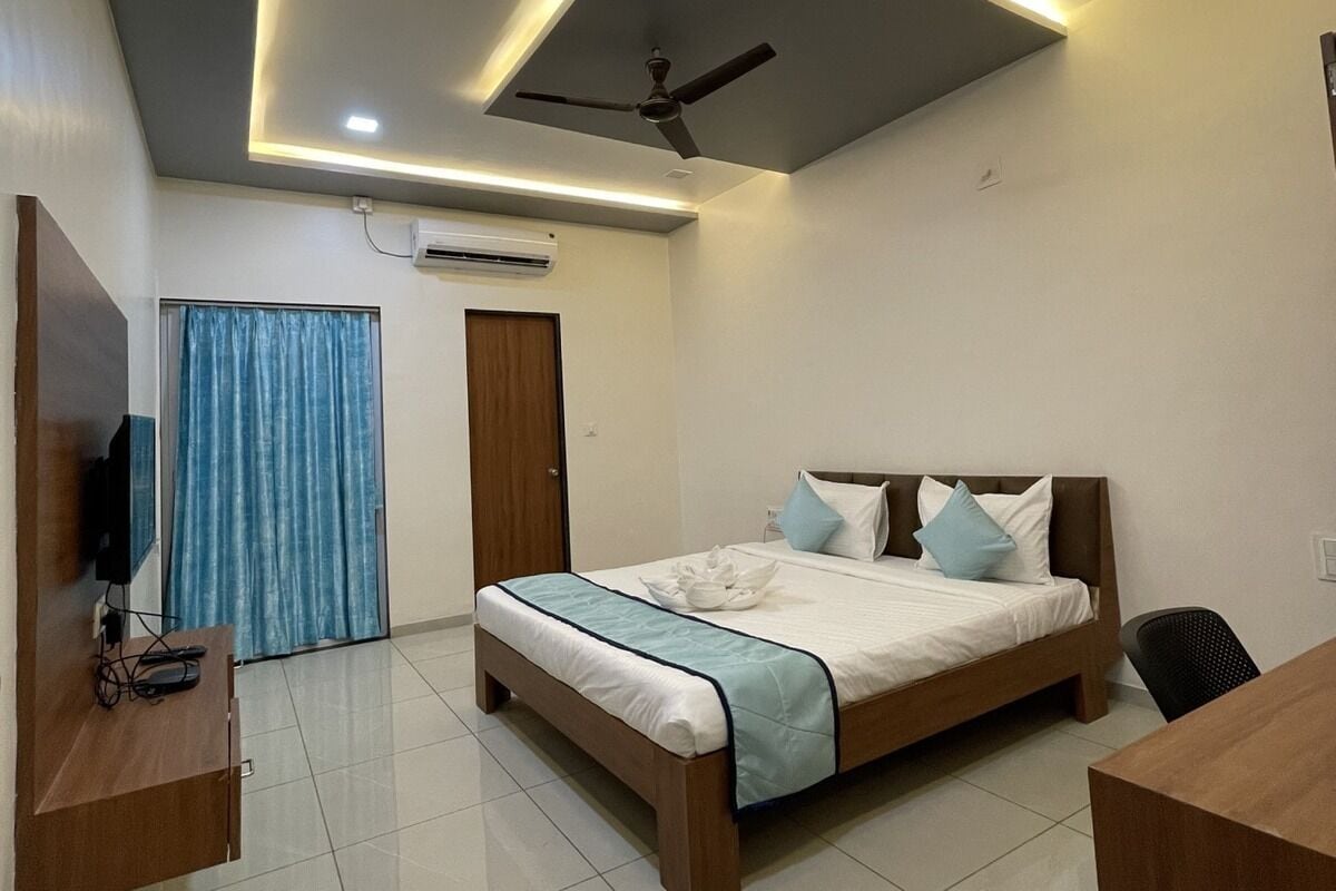 Un dormitorio moderno con cama, escritorio, silla, ventilador de techo y aire acondicionado.