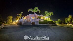 A well-lit, two-story house with a gated entrance, palm trees, and a stone pathway leading to the driveway. - Elegant Huge Villa Large Pool, Ideal For Weddings (Kathikas)