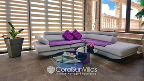 A modern living room with a sectional sofa, a glass coffee table, and a potted plant. - Elegant Huge Villa Large Pool, Ideal For Weddings (Kathikas)