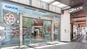 Een hotelentree met een glazen gevel, borden met 'OAKS Hotels & Resorts' en een zichtbaar zwembad.