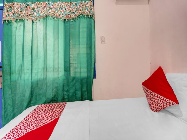 A room with a bed, a green curtain, and a red pillow.