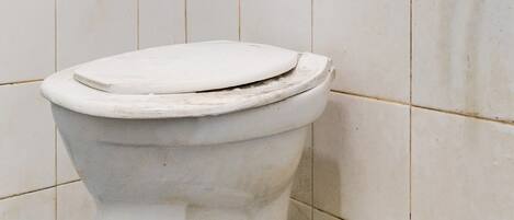 A toilet in a bathroom with white tiles and a blue and white patterned floor.