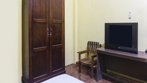 A room with a wooden wardrobe, a television on a wooden stand, and a wooden chair. - OYO 91855 Big Hotel Kendari (Kendari)