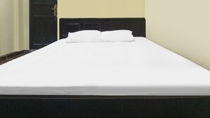 A single bed with white bedding in a room with a dark headboard and light walls. - OYO 91855 Big Hotel Kendari (Kendari)
