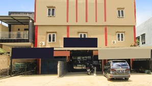 A multi-story building with a flat facade, a covered entrance, and a parked car. - OYO 91855 Big Hotel Kendari (Kendari)