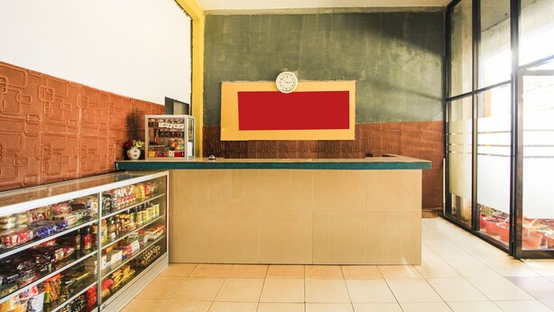 A reception area with a counter, a clock, and a display board. - OYO 91855 Big Hotel Kendari (Kendari)
