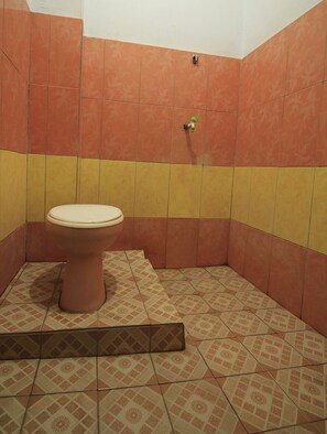 A bathroom with a toilet, patterned tiles, and a yellow and orange color scheme.