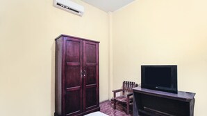 A room with a wooden wardrobe, a television on a stand, and an air conditioning unit on the wall. - OYO 91855 Big Hotel Kendari (Kendari)