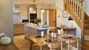Een moderne keuken met houten kasten, een centraal eiland en een eethoek met een houten tafel en stoelen.