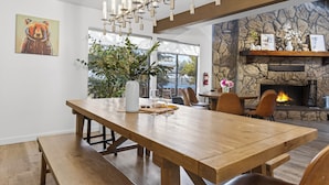 Una mesa de madera para comer con bancos, una chimenea de piedra y una araña.