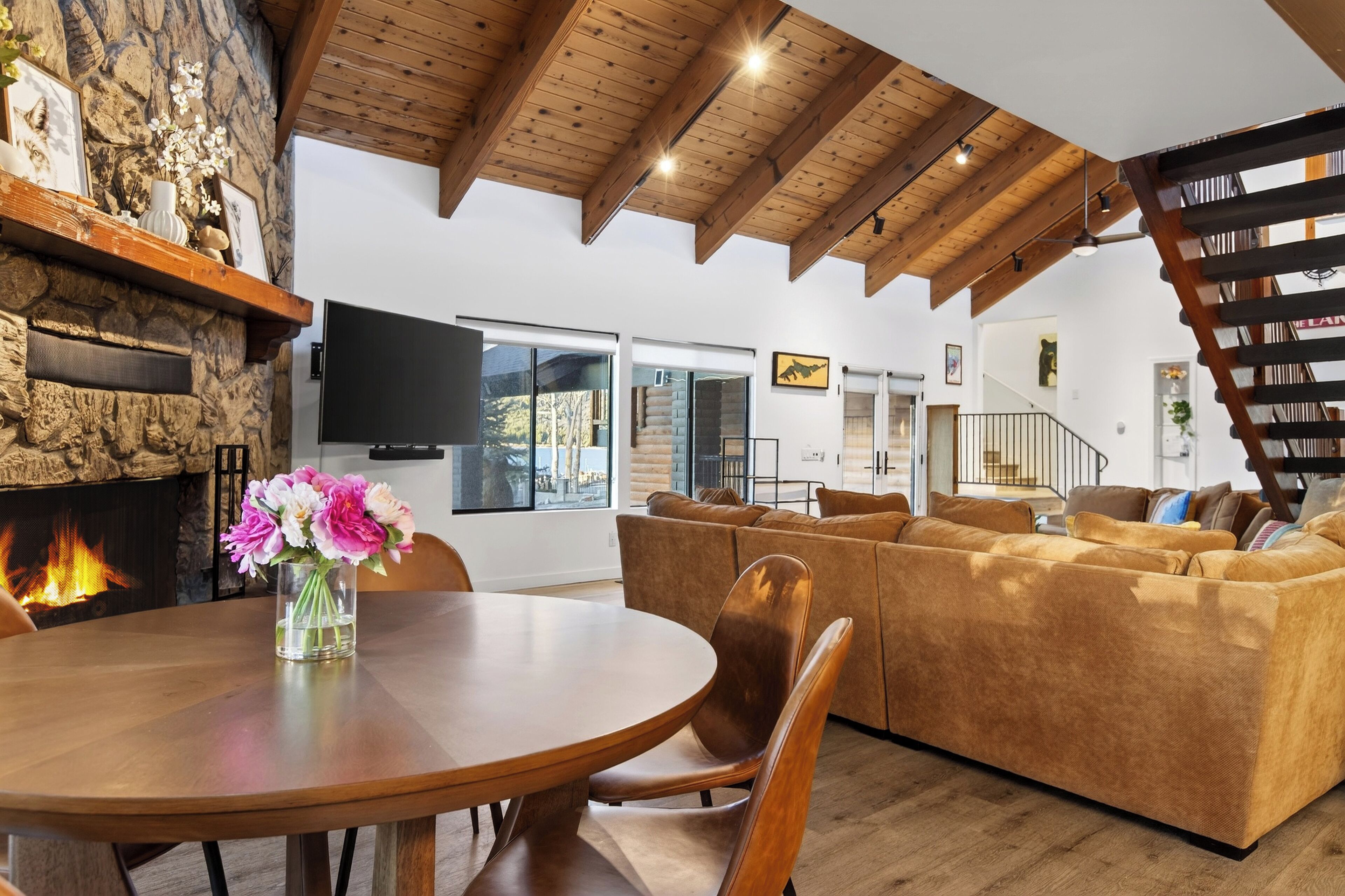 Ein modernes Wohnzimmer mit Kamin aus Stein, einem Holzesstisch und einem braunen Sofa.