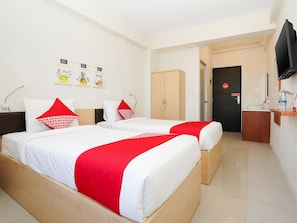 A hotel room with two beds, a wooden wardrobe, a desk with a TV, and a bathroom door. - OYO 91964 Menara Rungkut Surabaya (Surabaya)